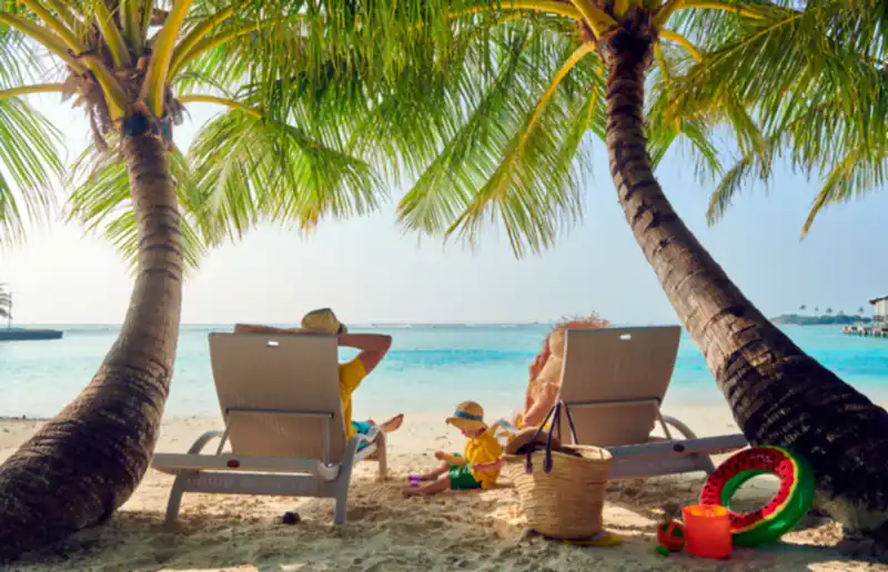 A family on sunbeds under palm trees on a tropical beach